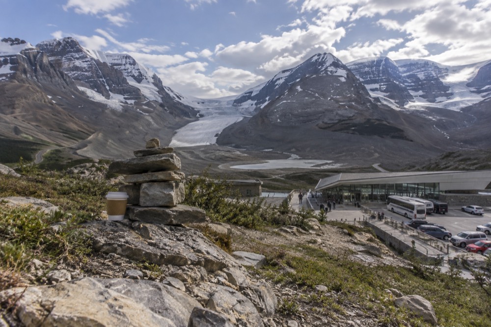 A vast snow and ice plateau stretching between jagged mountain summits under scattered clouds