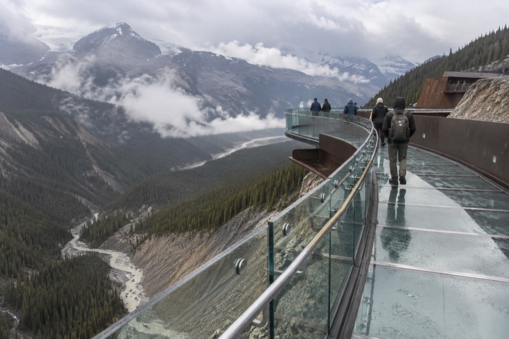 A glass-floored walkway extending along a cliff edge above a deep glacial valley