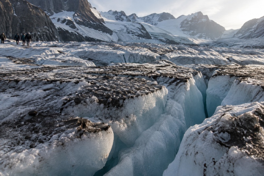 The crumpled, cracked surface of a glacier tongue with deep blue crevasses between ice ridges