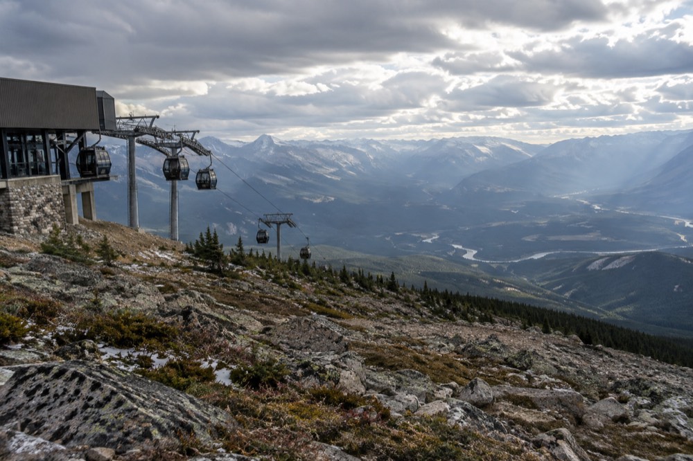 Gondola cabins parked at an upper mountain station above alpine meadows