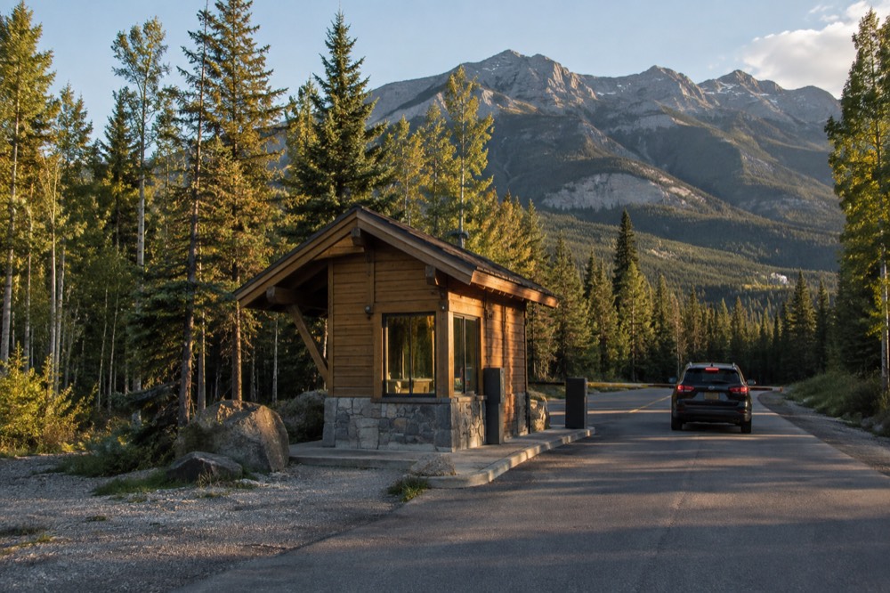 Entry gate kiosk at a national park entrance with forested mountains behind