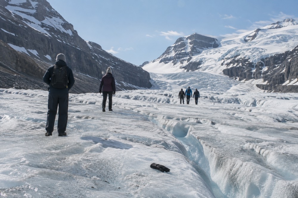 Visitors in warm jackets standing on the surface of the Athabasca Glacier