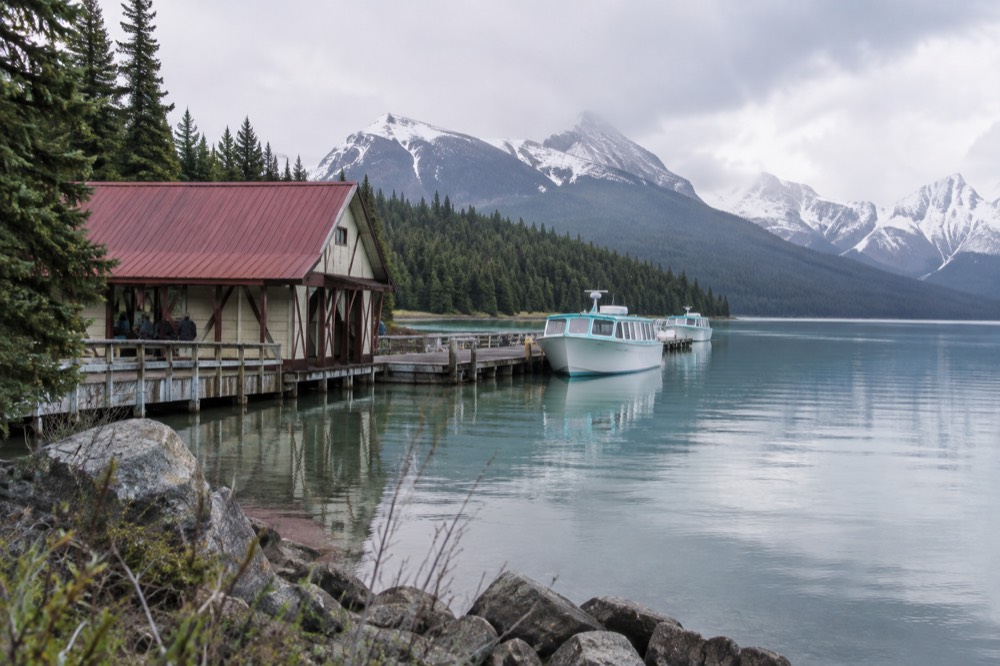 A calm glacial lake surrounded by forested valley slopes in the Maligne Valley