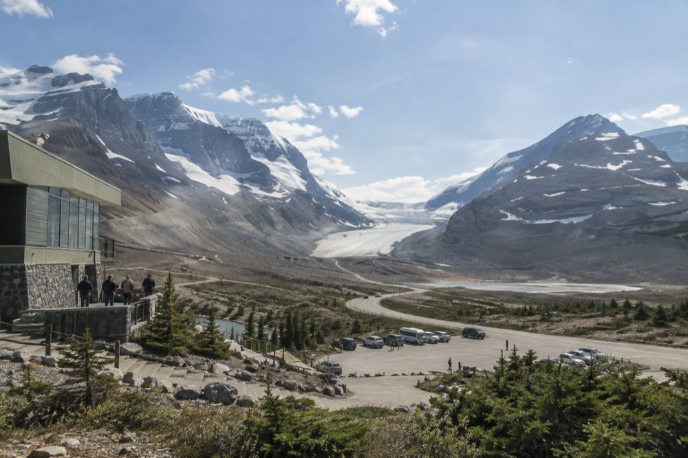 The Icefields Parkway curving through a wide mountain valley toward the Columbia Icefield, with the Athabasca Glacier visible in the distance.