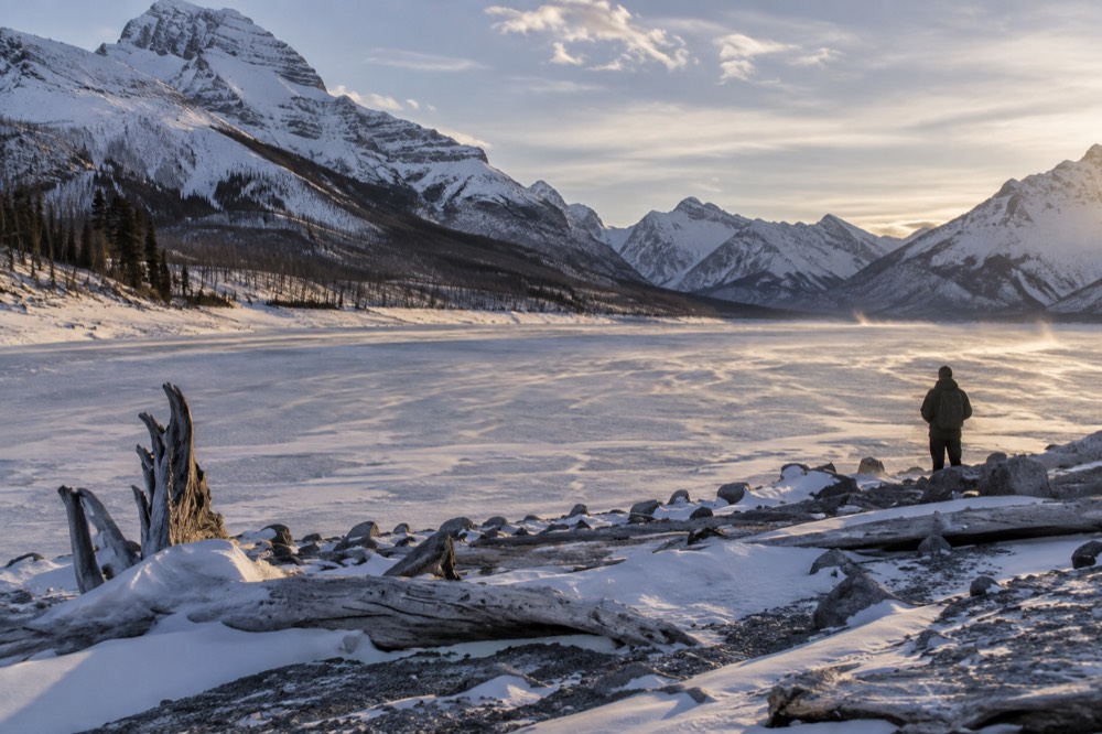 A snow-covered valley with frozen lake ice and low winter light on distant peaks