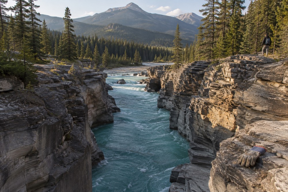 Narrow limestone canyon walls rising above a turquoise river in a forested mountain valley