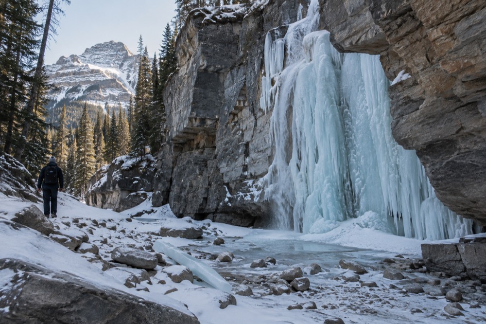 A frozen waterfall of blue ice clinging to tall grey canyon walls