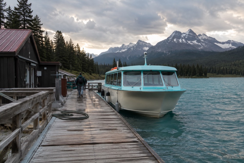 A covered tour boat moored at a wooden dock on a large mountain lake