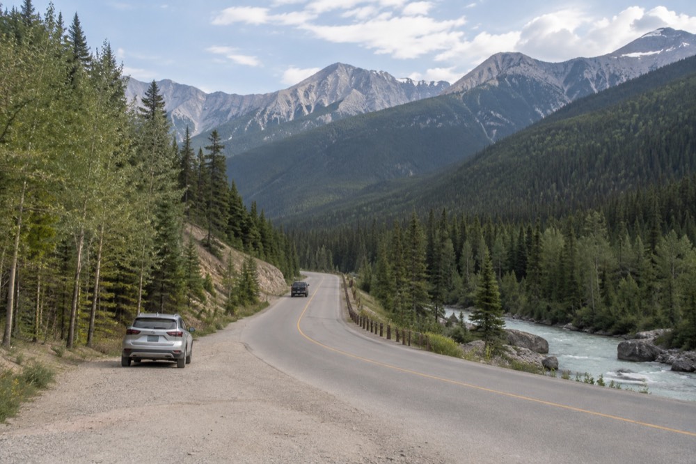 Winding mountain road following a river valley toward forested peaks