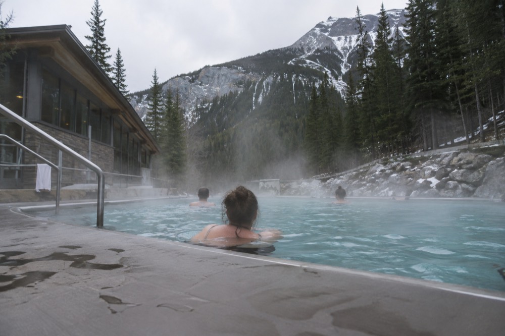 Steam rising off outdoor hot pools with a rocky mountainside behind them