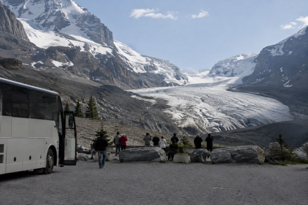 Glacier tongue flowing down between dark rock walls with a viewing walkway in the foreground