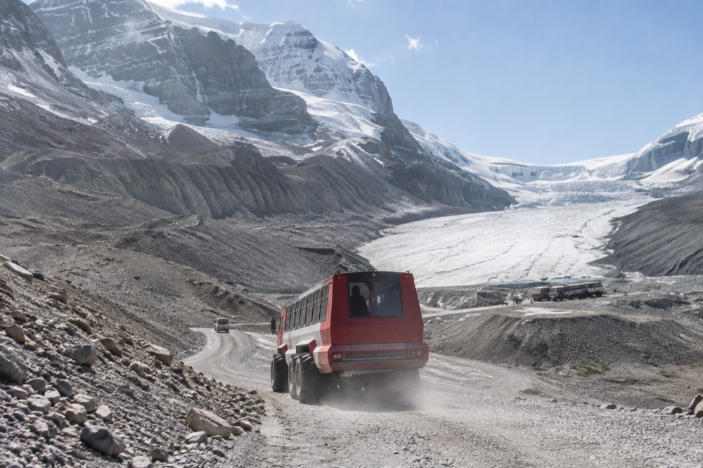 An Ice Explorer vehicle descending a steep track toward the Athabasca Glacier ice surface