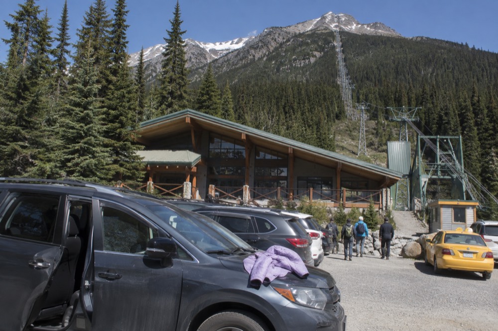 Taxi and visitor vehicles parked near a mountain gondola station