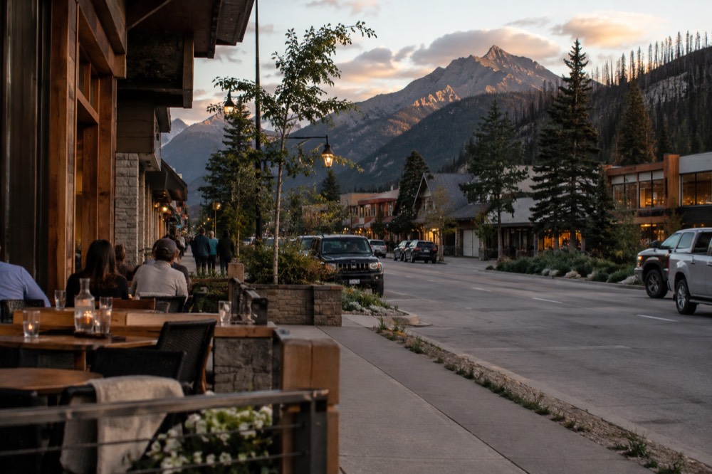 A small mountain town street with restaurants and shops under evening light
