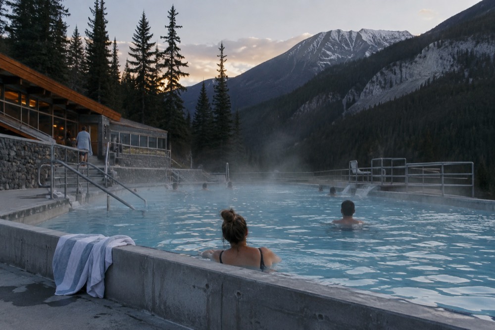 Steam rising from an outdoor hot spring pool surrounded by mountain forest