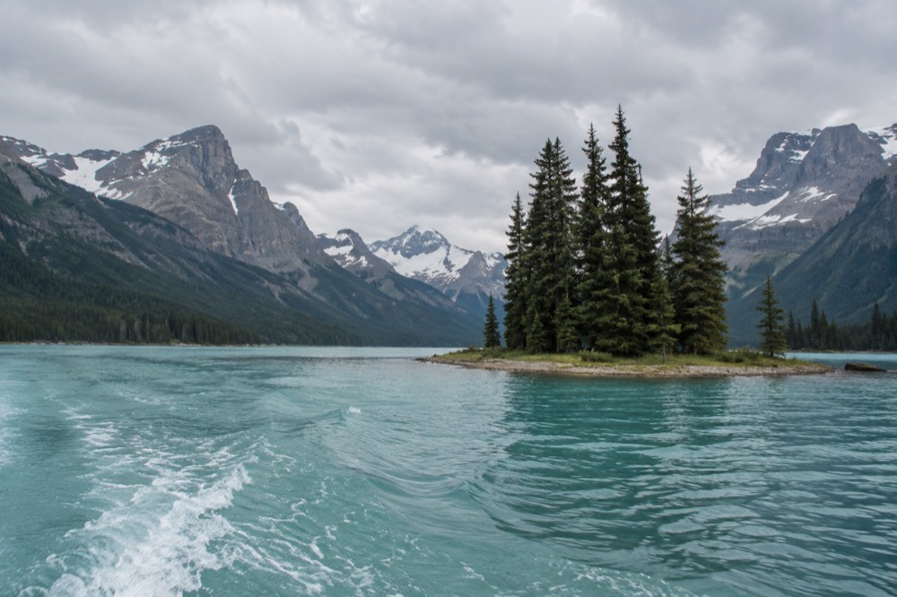 A turquoise mountain lake surrounded by forest with a small island near the shore