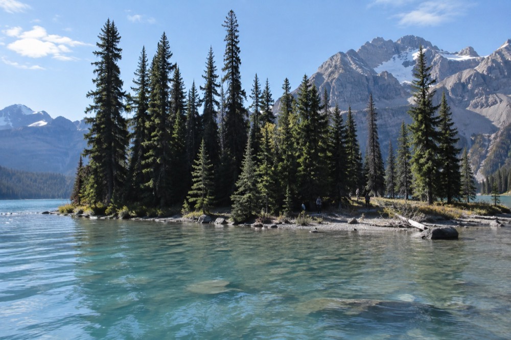 Spirit Island with dense forest and a mountain ridge behind it, seen from the water
