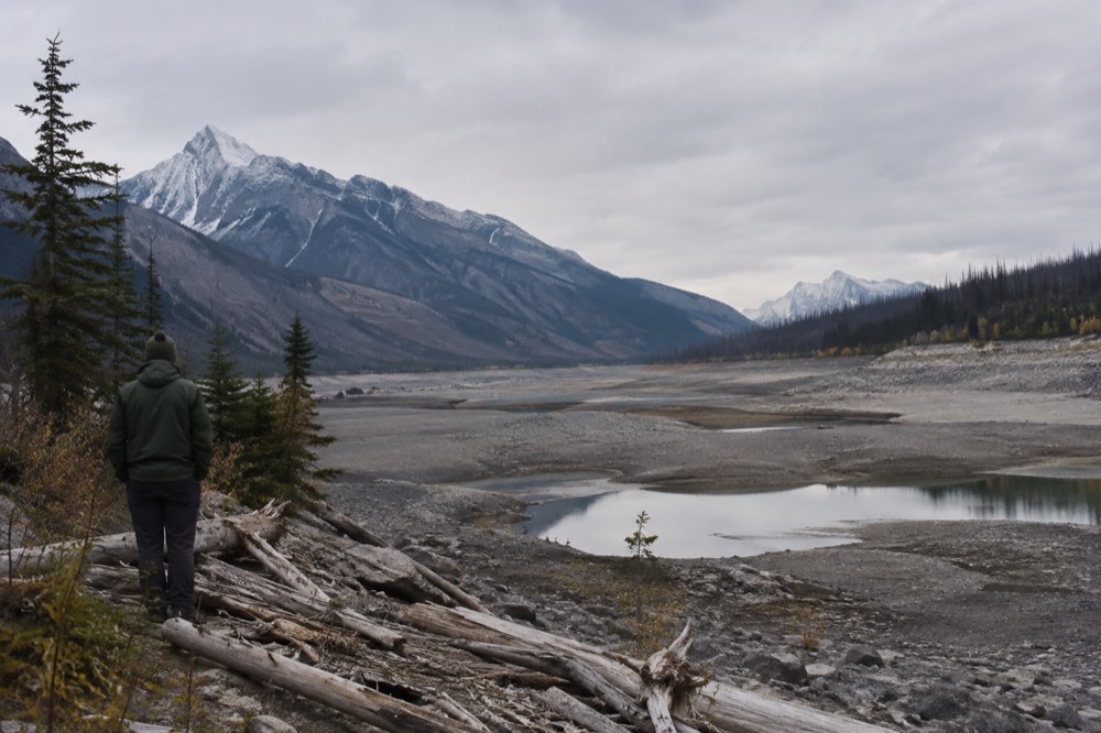 A partly drained mountain lake with exposed shoreline and forested slopes