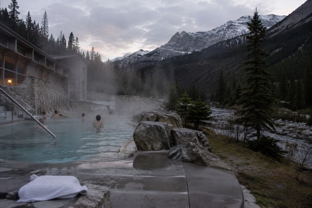 Steaming hot spring pools beside a mountain creek in a forested valley