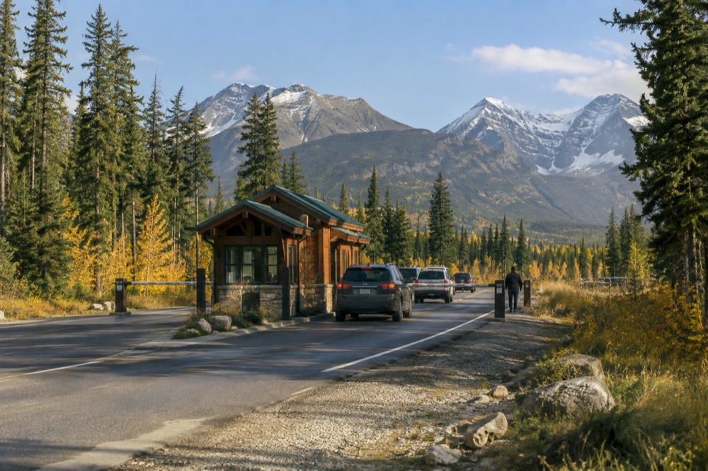 Park entry gate booth on a forested highway with mountains behind