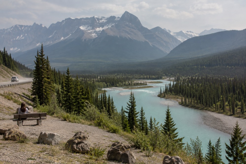 A deep mountain valley with a winding road beside a turquoise river