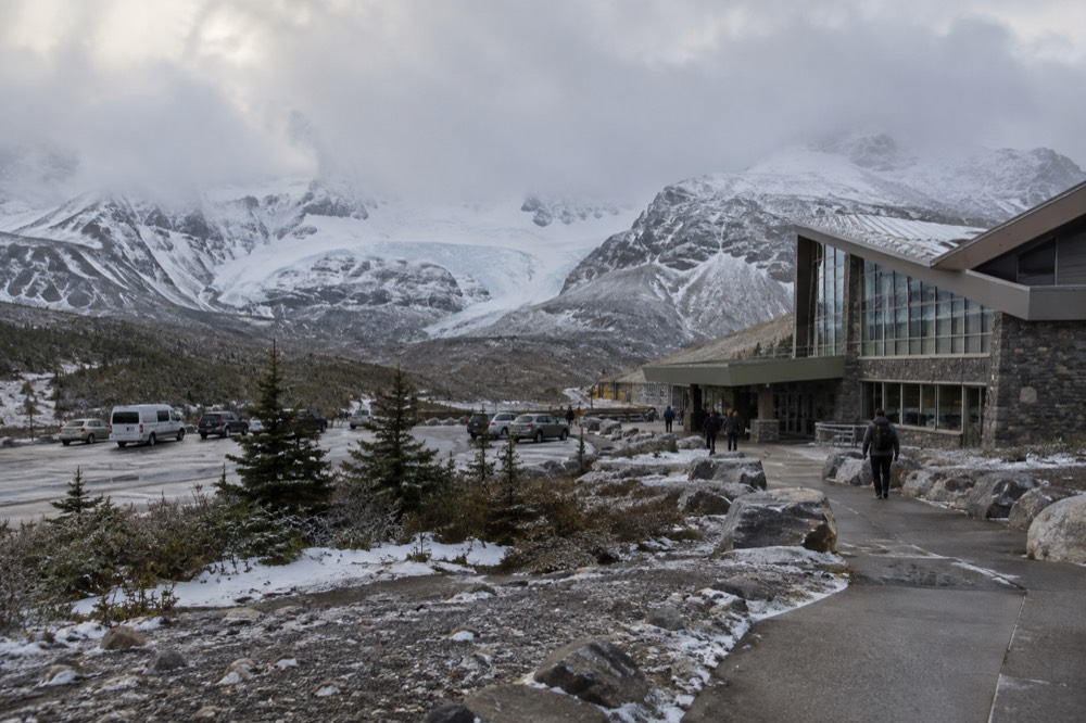 A wide glacial valley in morning light with low clouds resting on the peaks around a large icefield