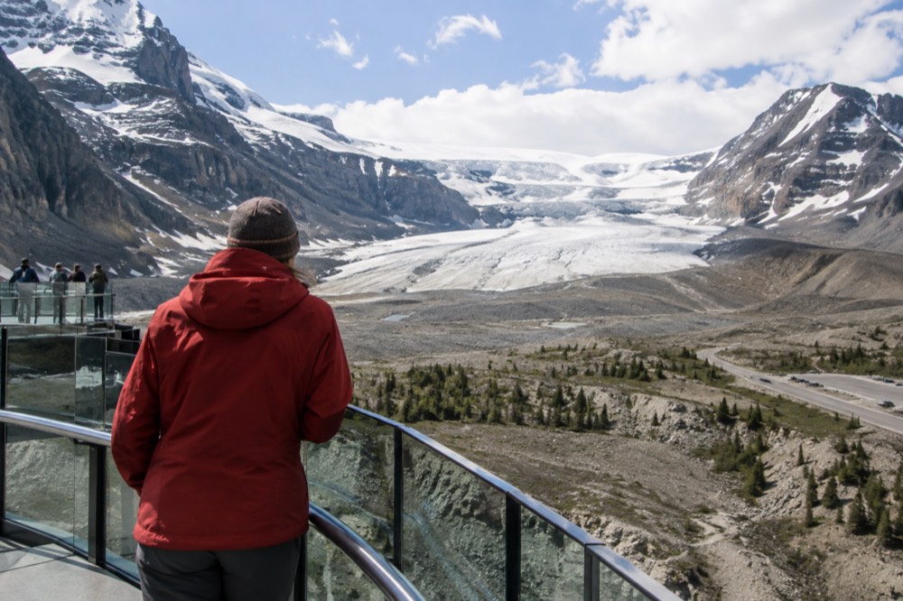 A visitor in a warm jacket looking out over the glacier from the Skywalk viewpoint