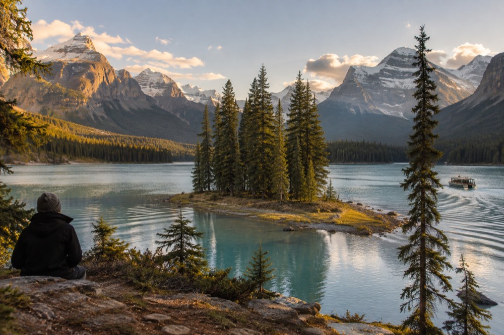 A small forested island in a blue mountain lake surrounded by peaks