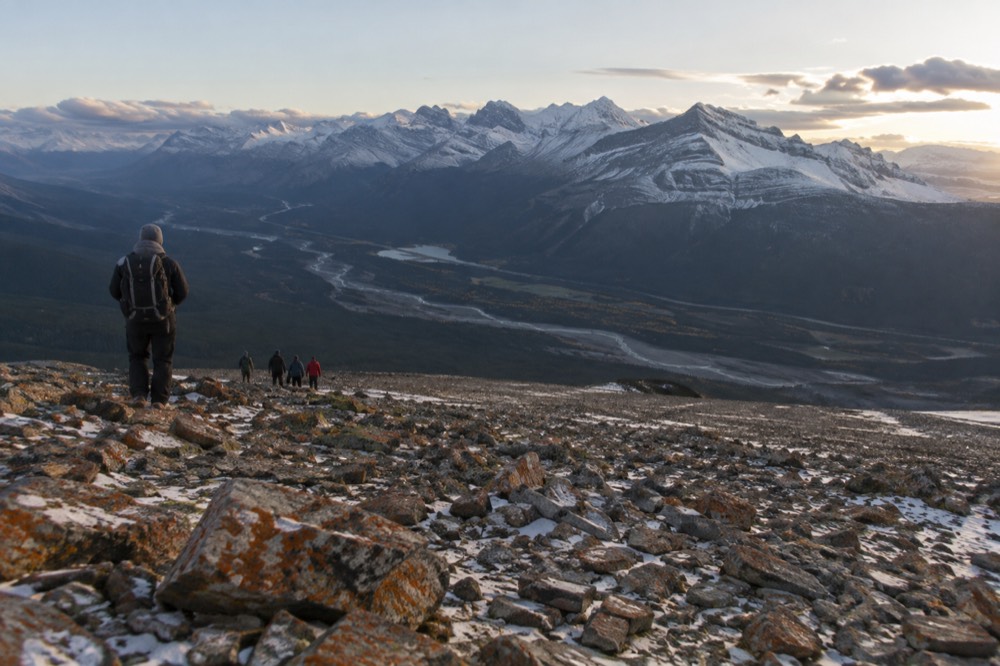 A guide leading a small group along a mountain viewpoint above a river valley