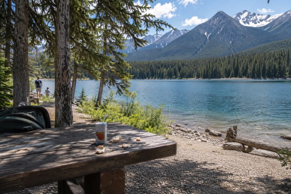 A wooden day-use picnic area beside a turquoise lake in Jasper National Park