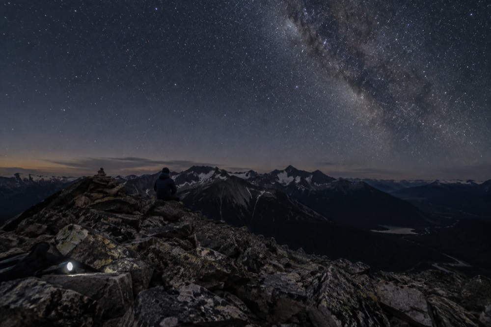 A wide night sky filled with stars above dark mountain silhouettes
