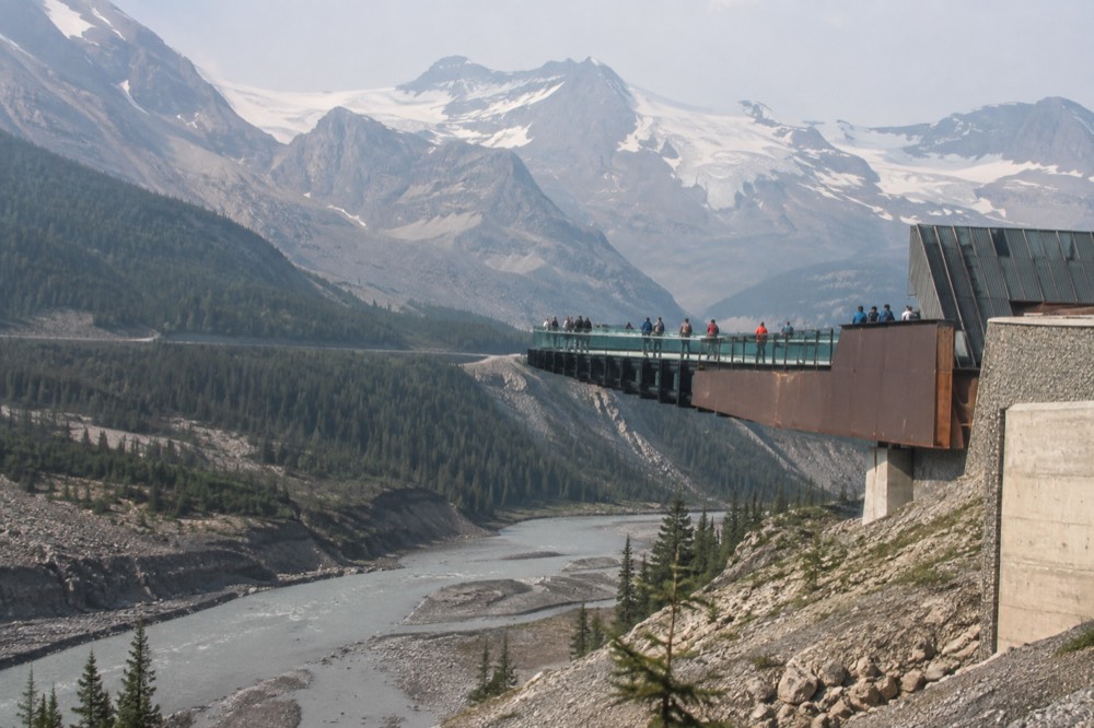 A glass-floored walkway curving along a cliff edge above a river valley