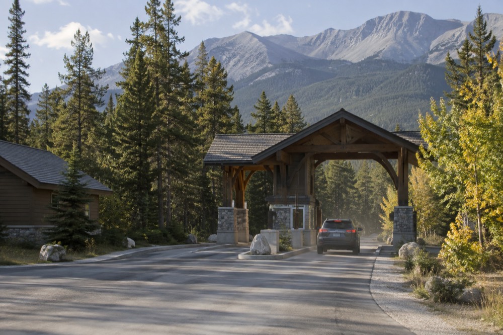 A park entrance gate booth beside a forested highway in morning light