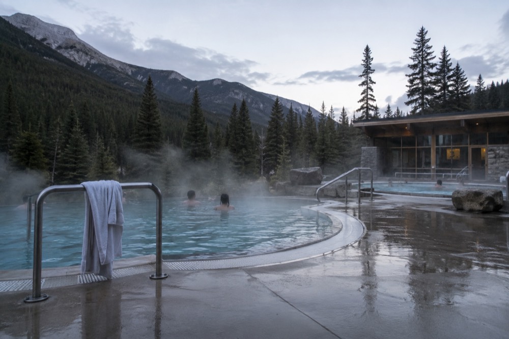 Steam rising from hot spring pools surrounded by mountain forest