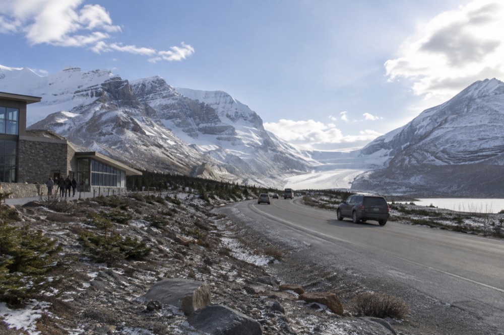 A highway winding between mountains with a glacier in the distance