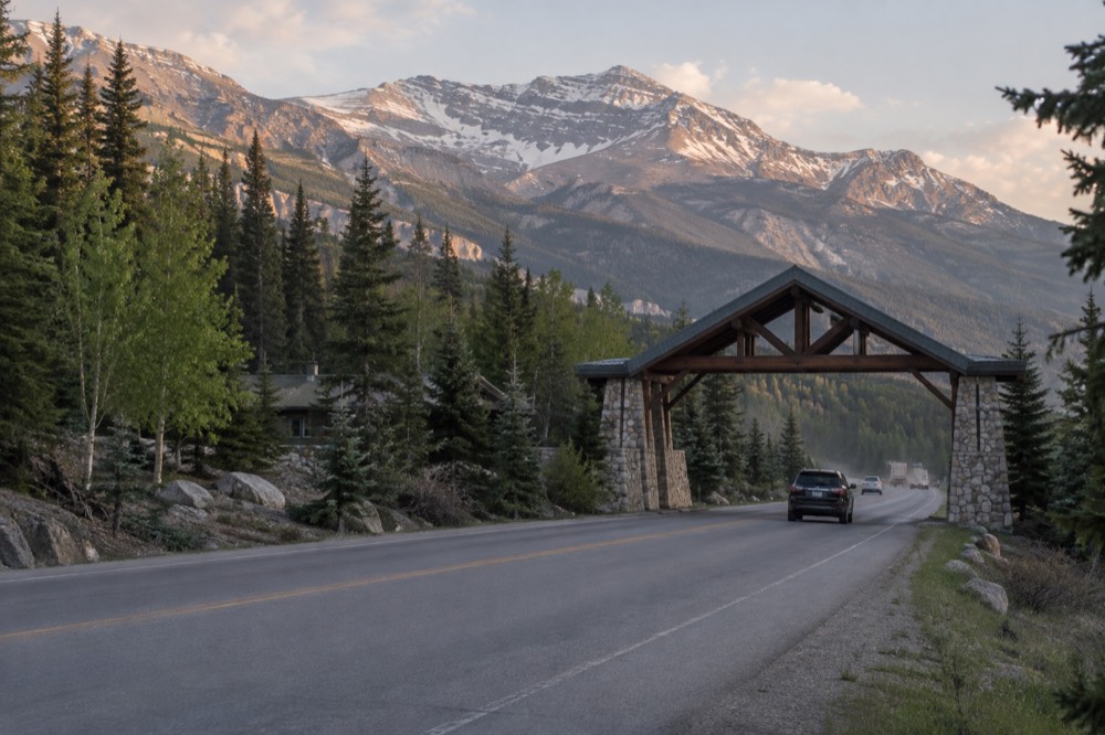 A park entry gate with a signboard and forested mountains behind it