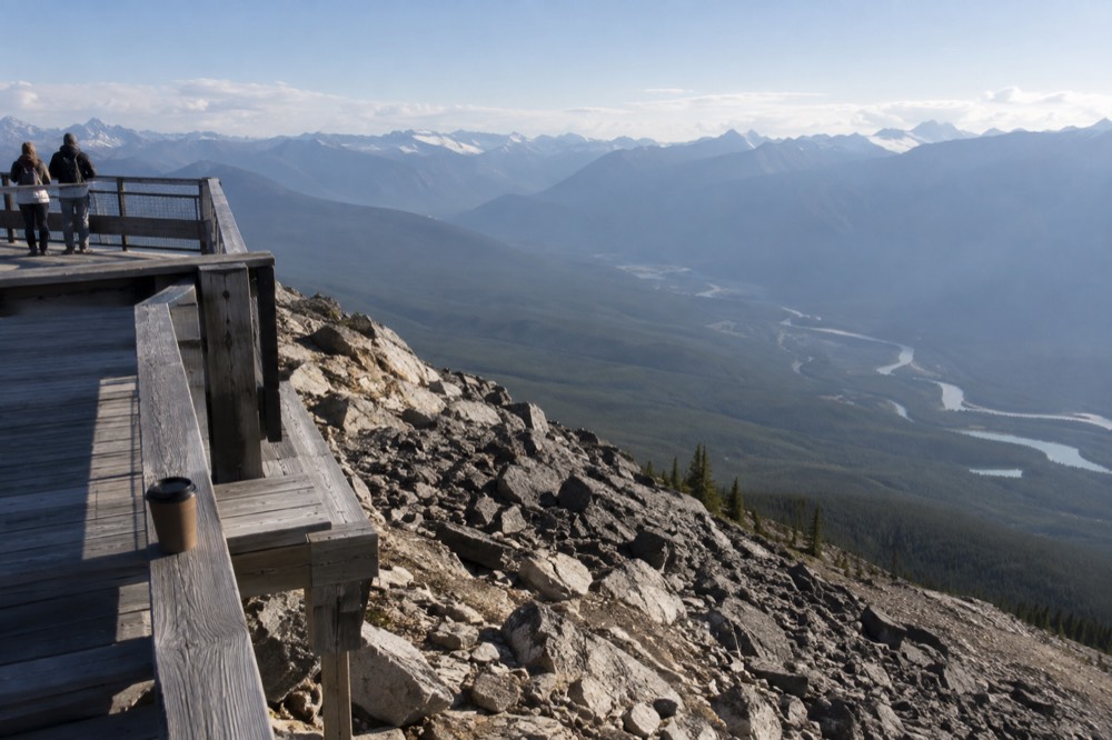 Wooden boardwalk and viewing deck at a mountain upper station with wide valley views below