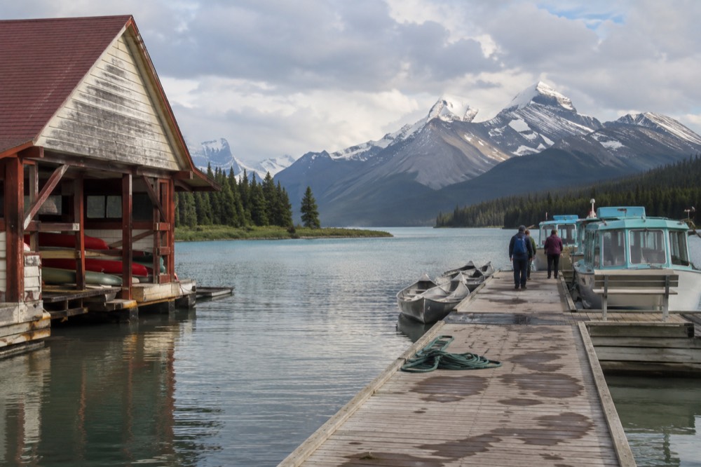 A wooden boathouse dock on a long lake surrounded by forested mountains