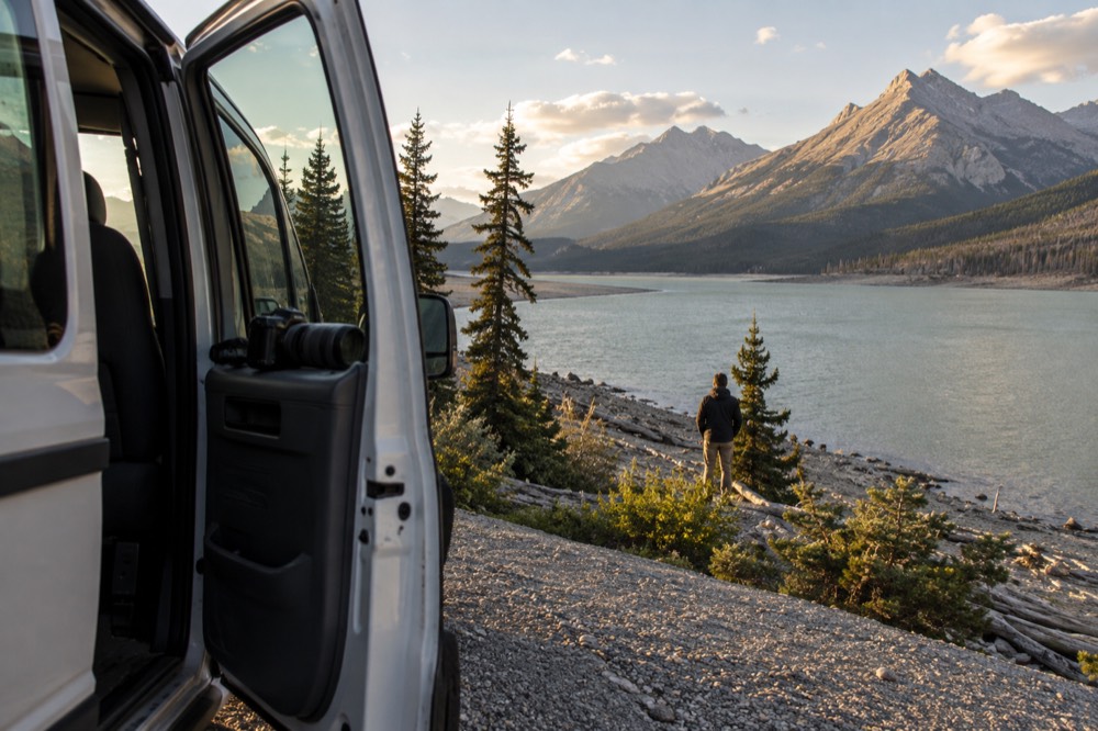 A guided tour van pulled over at a roadside viewpoint overlooking a river valley