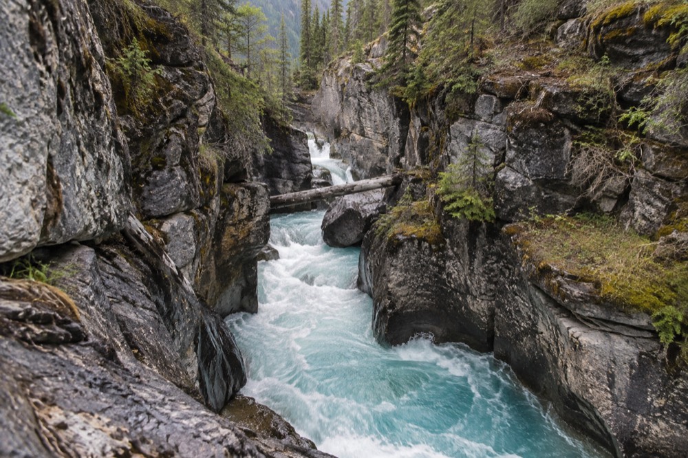 A narrow limestone gorge with turquoise water rushing between steep rock walls
