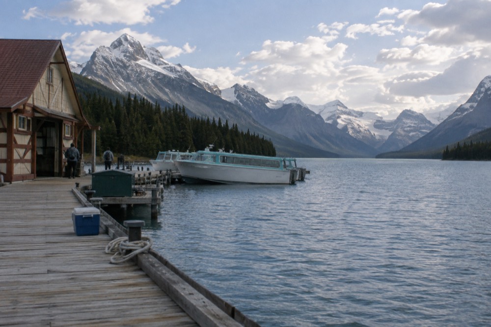 A long blue lake between mountain peaks with a small boat dock at the near shore