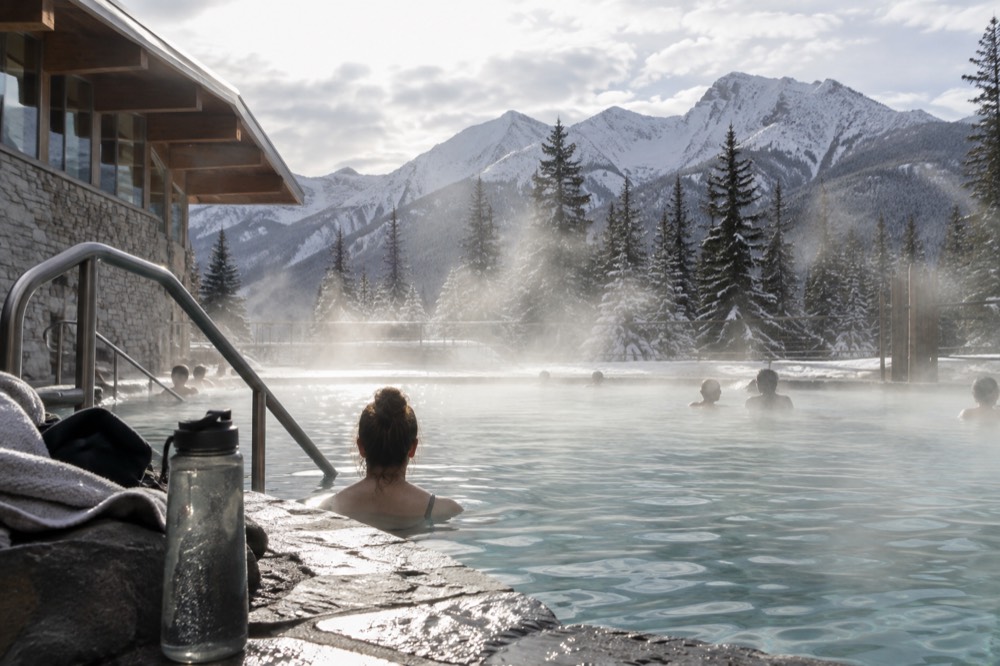 Steam rising off a hot pool with mountains reflected in the water
