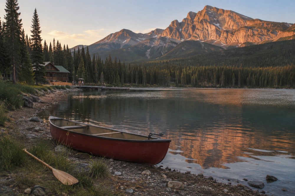 A canoe on a calm mountain lake at golden hour