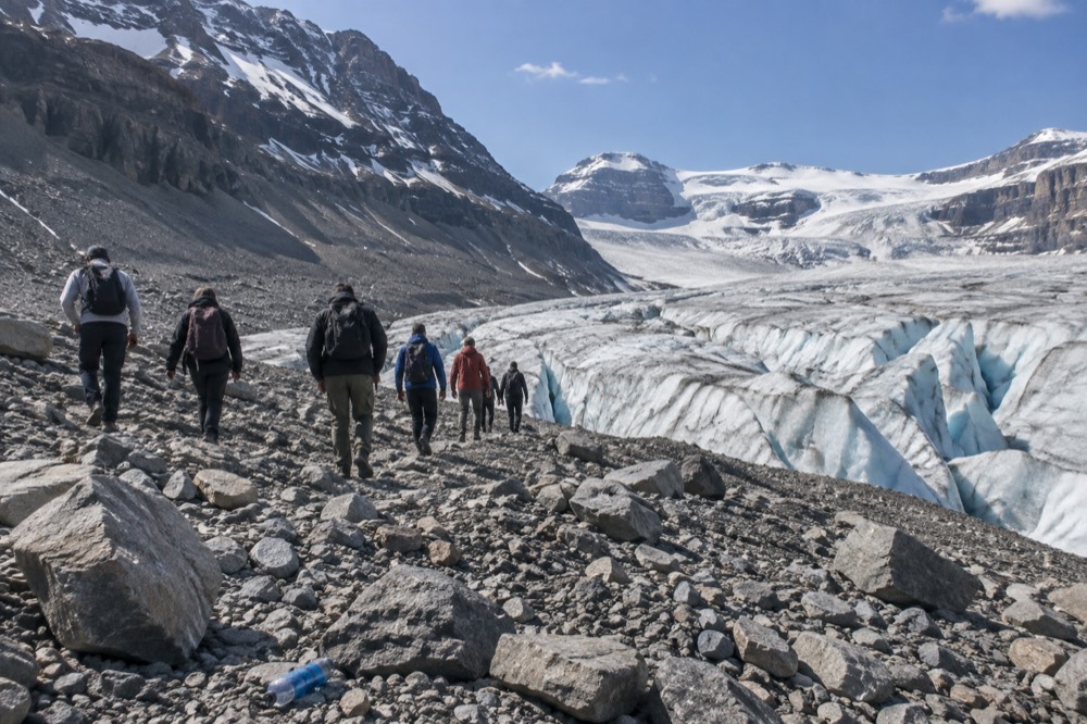 Guided walking group on a rocky glacier moraine under a bright sky