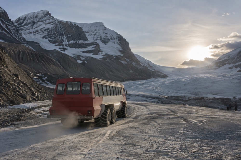 All terrain vehicle climbing a snow and ice slope toward a glacier tongue