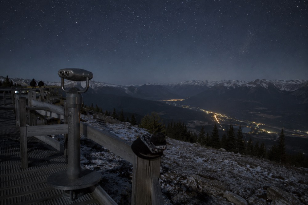 A telescope set up on a mountain boardwalk under a starry night sky