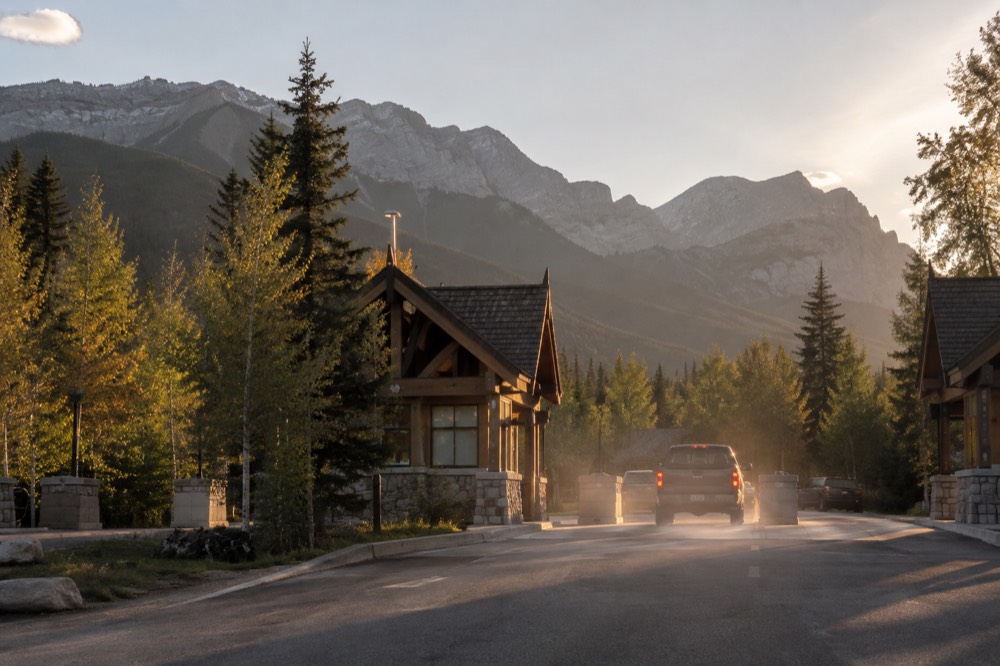 A park entry gate booth on a forested highway in late afternoon light
