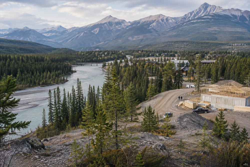 Wide valley with a winding turquoise river between forested slopes and distant snow-covered peaks
