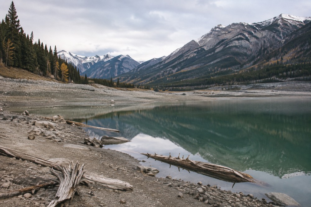 Long mountain lake with a small forested island near distant peaks reflected in still water