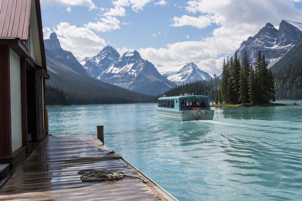 A tour boat crossing a long mountain lake toward a small forested island
